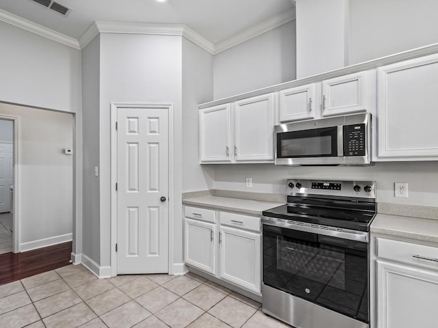 kitchen featuring stainless steel appliances, white cabinetry, ornamental molding, and light tile patterned flooring