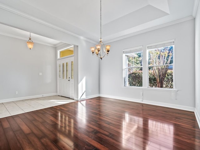 unfurnished room with hardwood / wood-style flooring, ornamental molding, and a notable chandelier