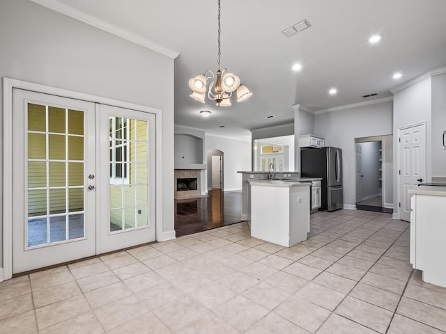 kitchen featuring ornamental molding, an inviting chandelier, white cabinetry, hanging light fixtures, and stainless steel refrigerator