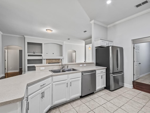 kitchen with white cabinets, stainless steel appliances, crown molding, and sink