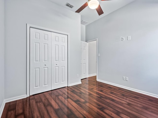 unfurnished bedroom featuring a closet, ceiling fan, dark hardwood / wood-style flooring, and a towering ceiling