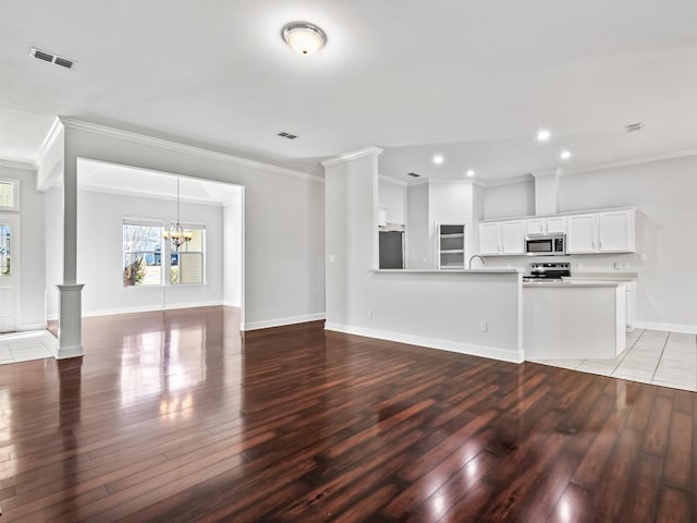 unfurnished living room featuring wood-type flooring, ornamental molding, and a notable chandelier