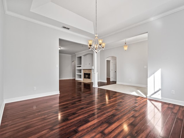 unfurnished living room with hardwood / wood-style floors, an inviting chandelier, and crown molding