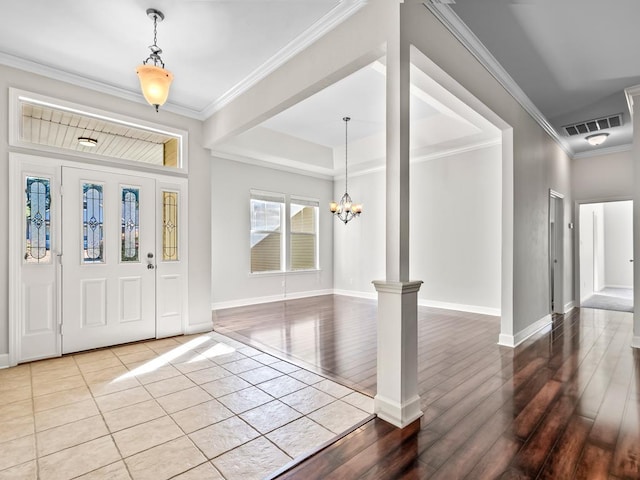 foyer entrance featuring decorative columns, crown molding, hardwood / wood-style floors, and an inviting chandelier