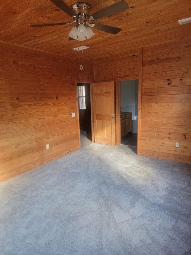 spare room featuring carpet flooring, wood walls, ceiling fan, and wood ceiling