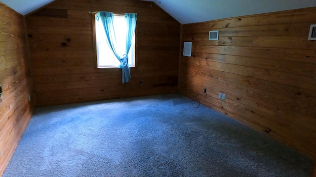 additional living space featuring carpet flooring, wooden walls, and vaulted ceiling