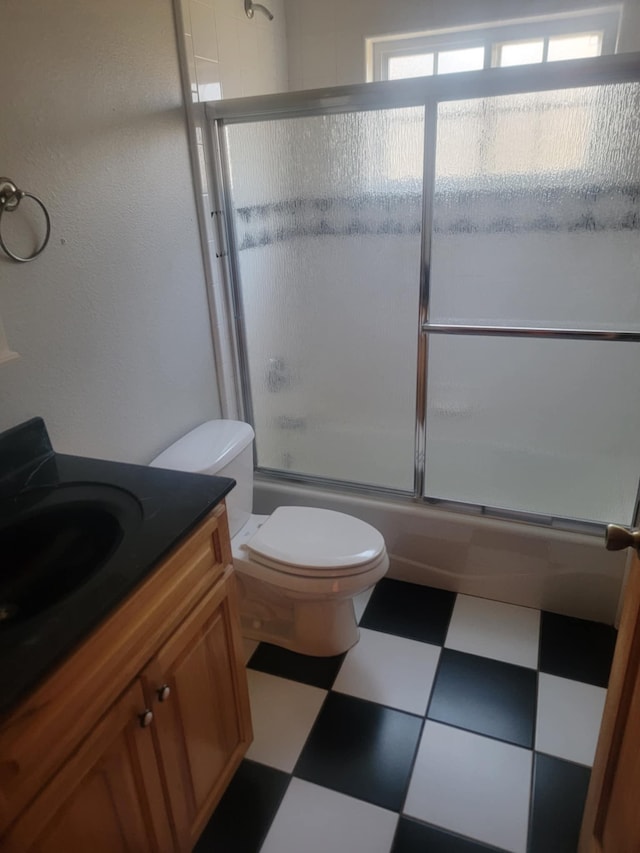 full bathroom featuring vanity, toilet, and shower / bath combination with glass door