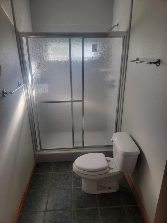 bathroom with tile patterned floors, a shower with shower door, and toilet