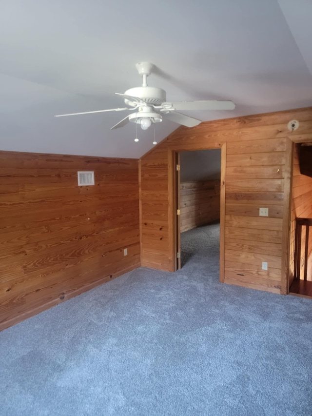 bonus room with ceiling fan, dark carpet, lofted ceiling, and wooden walls