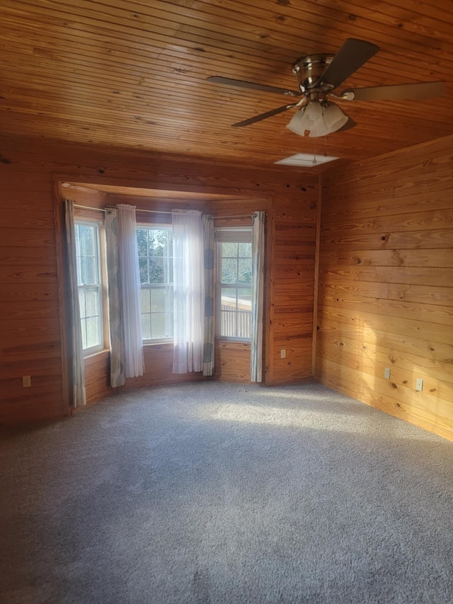 spare room featuring carpet flooring, wood walls, ceiling fan, and wood ceiling