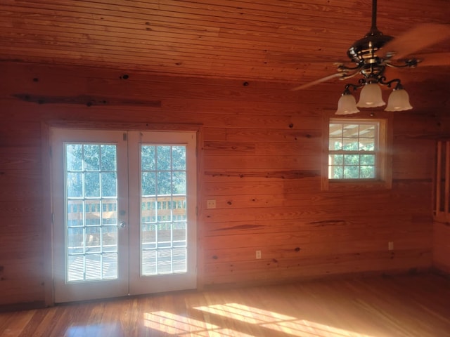 empty room featuring ceiling fan, hardwood / wood-style floors, wooden ceiling, and wooden walls