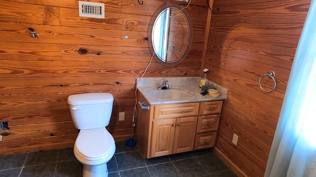 bathroom featuring tile patterned floors, vanity, toilet, and wood walls