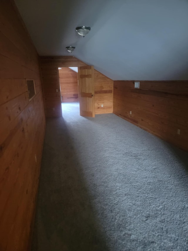 bonus room with carpet floors, wooden walls, and vaulted ceiling
