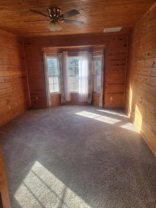 spare room with carpet flooring, ceiling fan, wood ceiling, and wooden walls