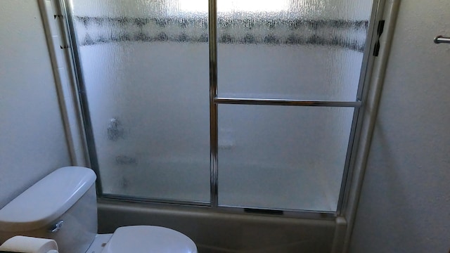 bathroom with shower / bath combination with glass door and toilet