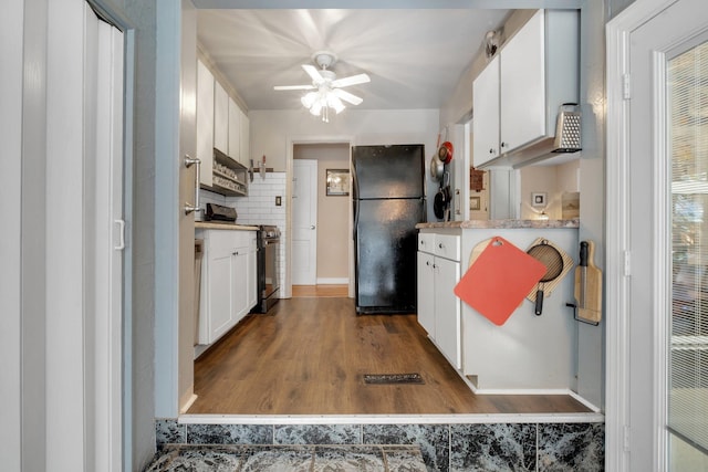 kitchen featuring black refrigerator, ceiling fan, backsplash, stainless steel electric stove, and white cabinets