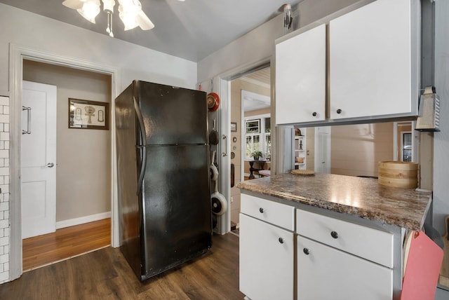 kitchen featuring black refrigerator, ceiling fan, dark hardwood / wood-style floors, dark stone countertops, and white cabinets