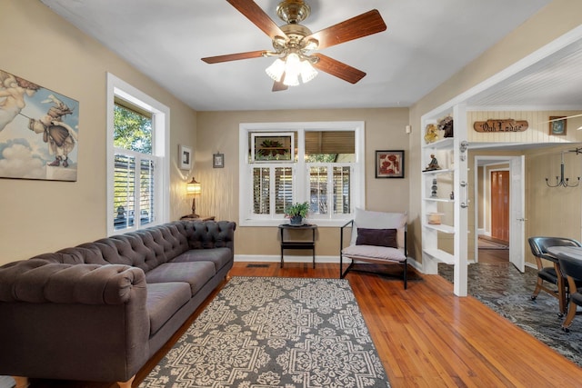 living room with ceiling fan, hardwood / wood-style floors, and built in shelves