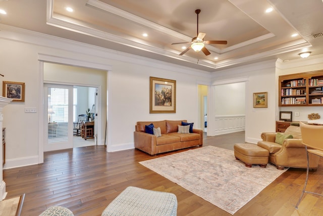 living room featuring crown molding, a tray ceiling, wood-type flooring, and ceiling fan