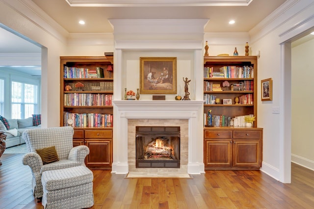 sitting room featuring crown molding, light hardwood / wood-style flooring, and a tile fireplace