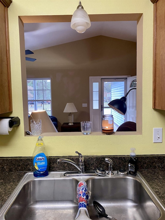 kitchen featuring sink, dark stone counters, and lofted ceiling