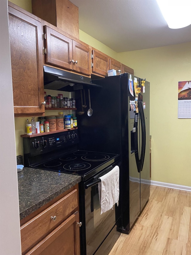 kitchen with light hardwood / wood-style flooring, dark stone countertops, and black / electric stove