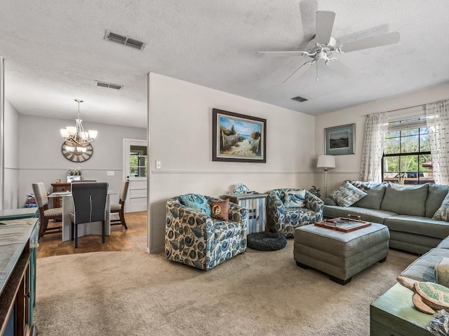 living room featuring visible vents, carpet, and ceiling fan with notable chandelier