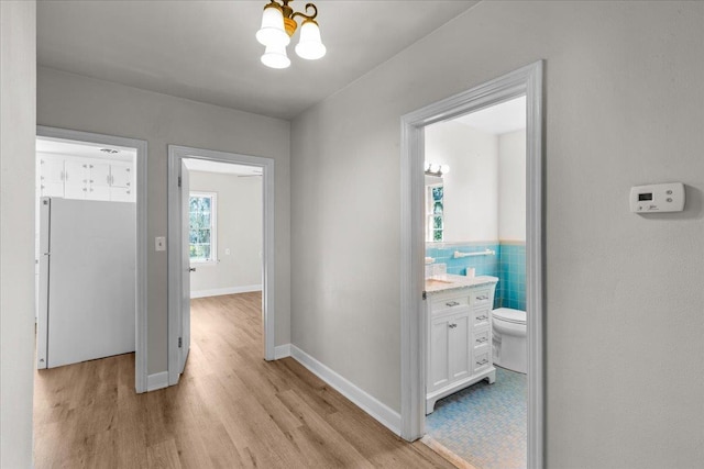 hallway with light hardwood / wood-style floors and a chandelier