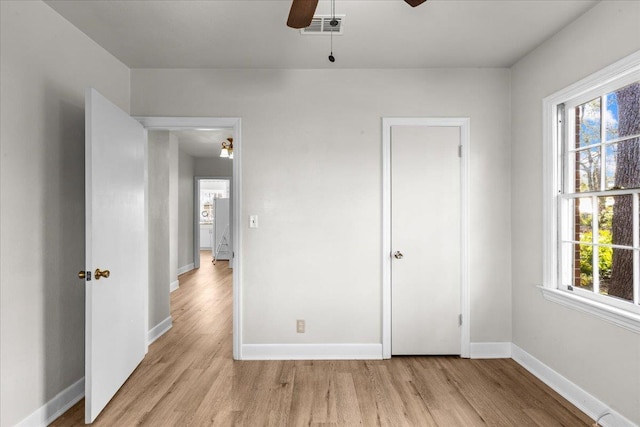 unfurnished bedroom featuring ceiling fan, light wood-type flooring, and multiple windows