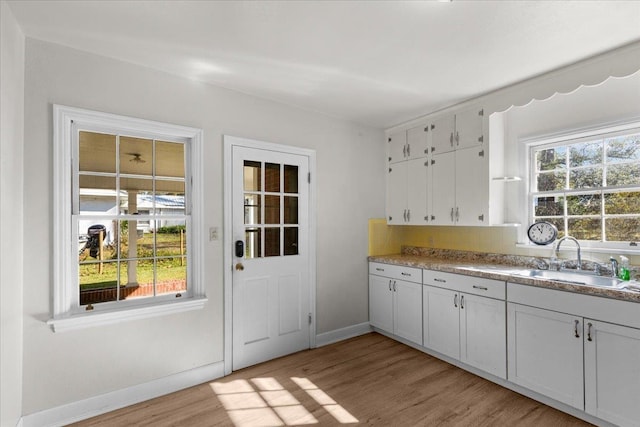 kitchen featuring white cabinets, light hardwood / wood-style floors, sink, and a wealth of natural light