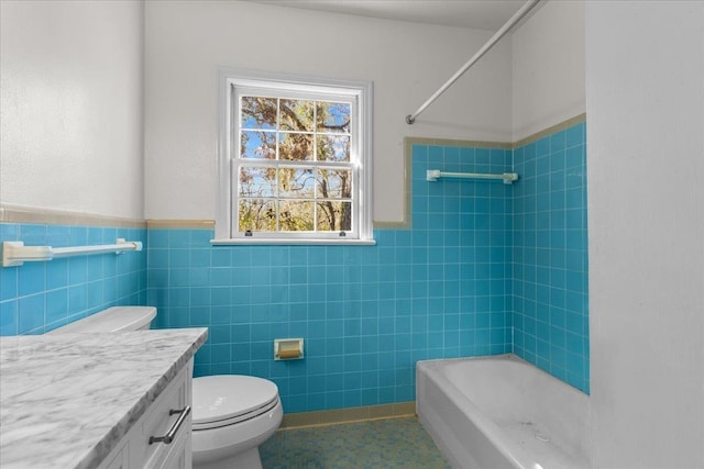 full bathroom featuring tiled shower / bath, vanity, toilet, and tile walls