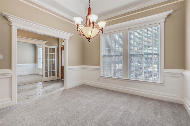 carpeted spare room featuring an inviting chandelier, crown molding, and a wealth of natural light