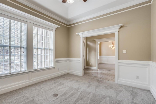 spare room featuring ornamental molding, ceiling fan with notable chandelier, a wealth of natural light, and light colored carpet