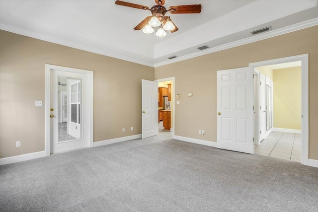 unfurnished bedroom with ornamental molding, light carpet, and a tray ceiling