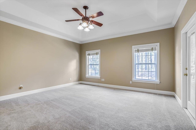 carpeted empty room with crown molding, ceiling fan, plenty of natural light, and a tray ceiling