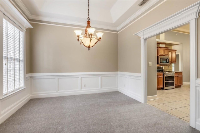 carpeted spare room featuring ornamental molding, a tray ceiling, and a notable chandelier