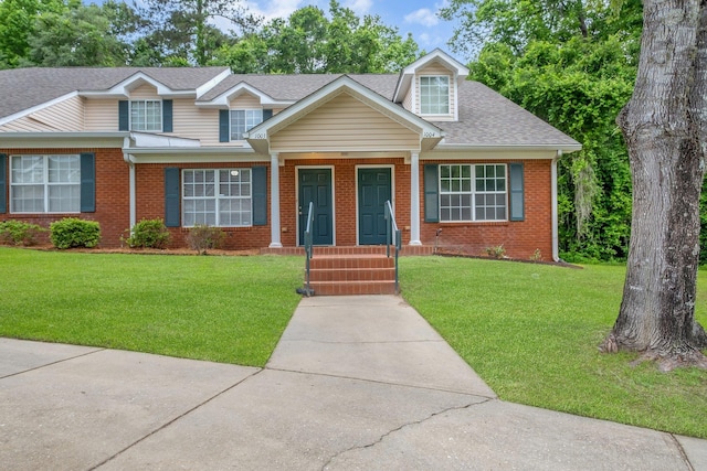 view of front facade featuring brick siding, a front yard, and roof with shingles