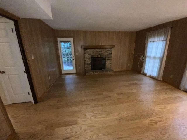 unfurnished living room featuring hardwood / wood-style flooring, a fireplace, and wooden walls