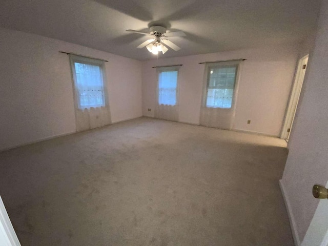 unfurnished room featuring ceiling fan, carpet, and a wealth of natural light