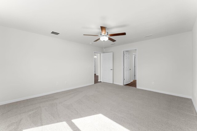 unfurnished room with ceiling fan and dark colored carpet