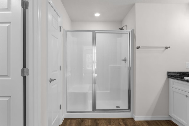 bathroom featuring vanity, wood-type flooring, and a shower with door