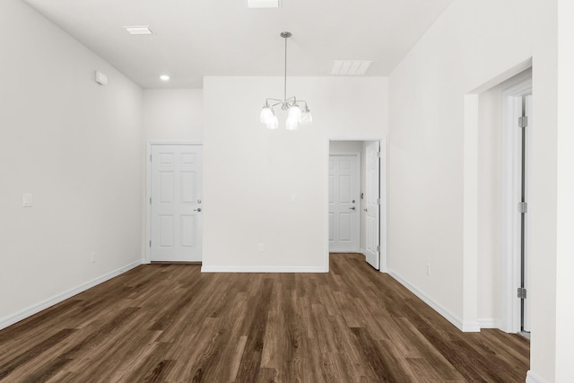 unfurnished dining area featuring dark wood-type flooring and an inviting chandelier