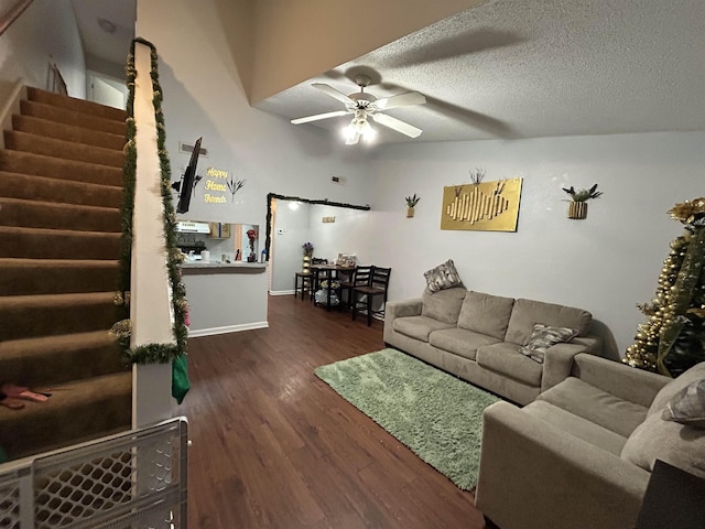 living room with ceiling fan, dark wood-type flooring, and a textured ceiling