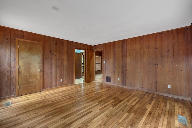 unfurnished room featuring wood walls and light wood-type flooring