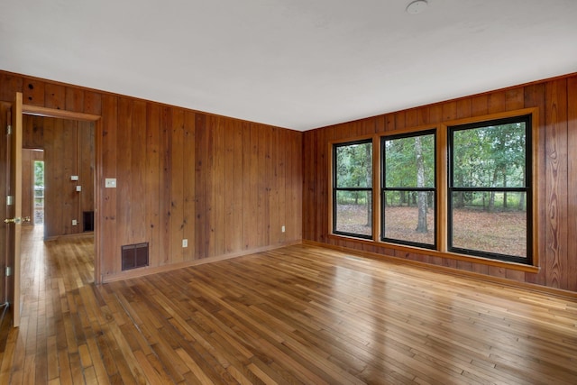 unfurnished room featuring wood walls and wood-type flooring