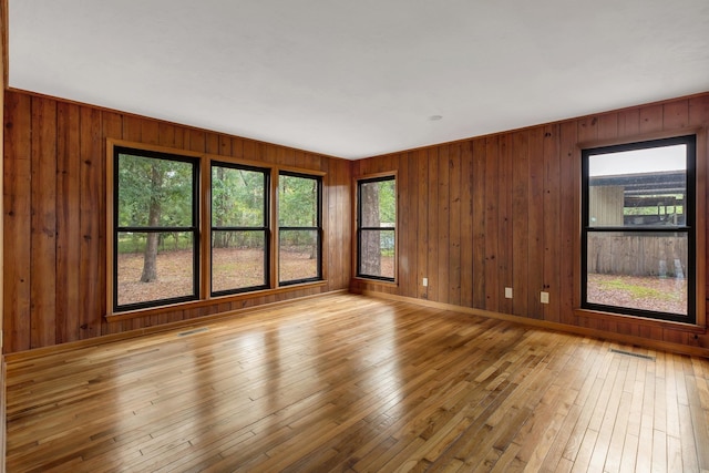 spare room featuring wood walls and light hardwood / wood-style flooring