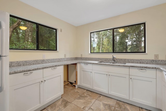 kitchen with white cabinets, sink, and light stone counters