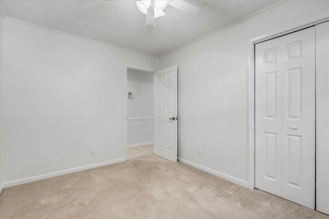 unfurnished bedroom featuring baseboards, ceiling fan, crown molding, carpet flooring, and a closet