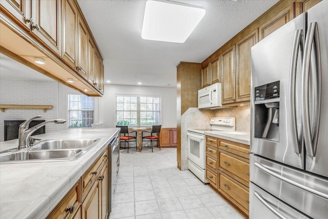 kitchen with brown cabinets, tasteful backsplash, light countertops, appliances with stainless steel finishes, and a sink