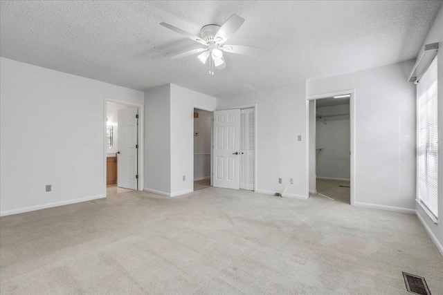 unfurnished bedroom with baseboards, visible vents, a textured ceiling, and light colored carpet